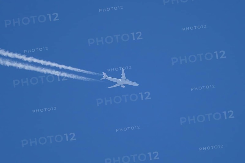 Jet passenger aircraft flying in a blue sky with contrails or vapour trails behind, England, United Kingdom