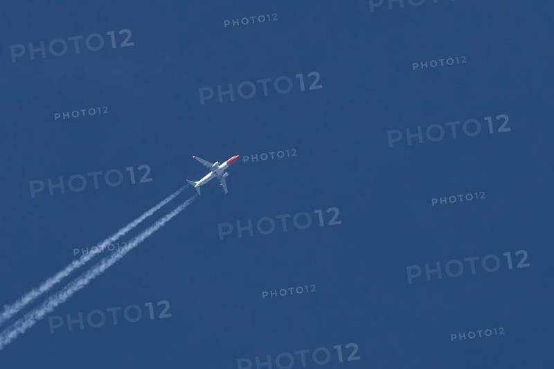 Boeing 737 jet passenger aircraft of Norwegian Air airlines flying in a blue sky with contrails or vapour trails behind, England, United Kingdom