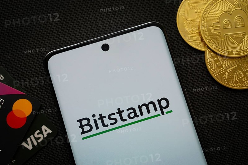Dhaka, Bangladesh- 06 Sep 2025: Smartphone displaying Bitstamp logo surrounded by Bitcoin coins and payment cards