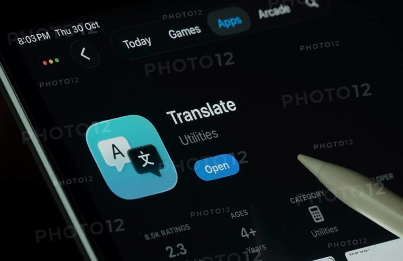 Dhaka, Bangladesh- 30 Oct 2025: Apple Translate app displayed on a iPad screen in dark mode with a digital pen pointing at it
