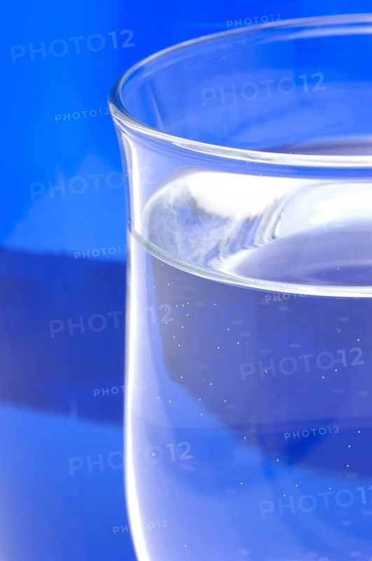 Glass with mineral water, small carbonated pearls on the edge of the glass, drinking water