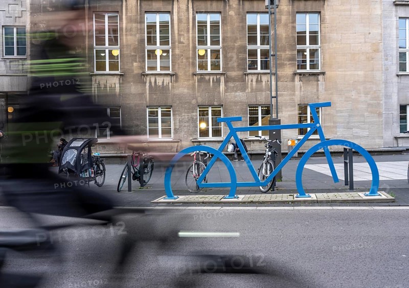 Bicycle parking spaces, with so-called leaning bars and a large blue bicycle silhouette, to make parking spaces visible at Bochum City Hall, North Rhine-Westphalia, Germany