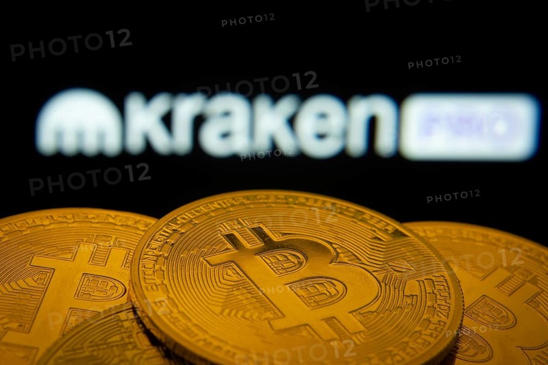 Dhaka, Bangladesh- 01 Nov 2025: Close-up of Bitcoin coins with the Kraken Pro logo visible on a screen in the background