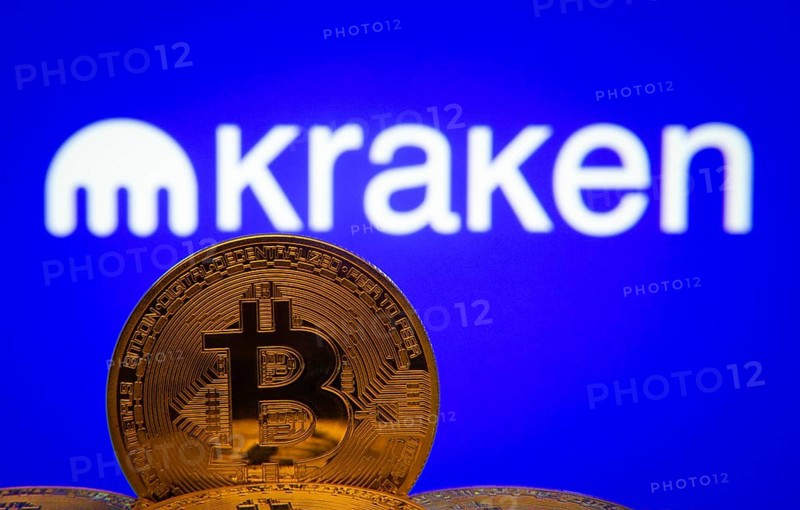 Dhaka, Bangladesh- 01 Nov 2025: Close-up of Bitcoin coins with the Kraken logo visible on a screen in the background
