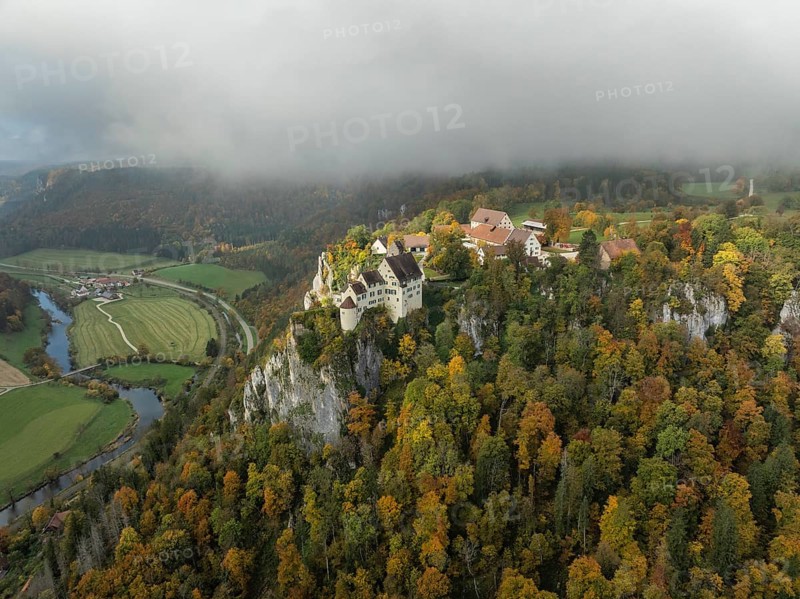 Aerial view of Werenwag Castle and former Werenwag Castle on a rocky spur in the Upper Danube Valley, surrounded by autumnal vegetation and clouds of fog, Sigmaringen district, Baden-Württemberg, Germany