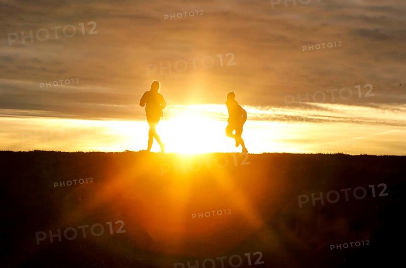 Woman and child walk across a dike on the island of Fehmarn at sunset, 13.10.2025, Fehmarn, Schleswig-Holstein, Germany