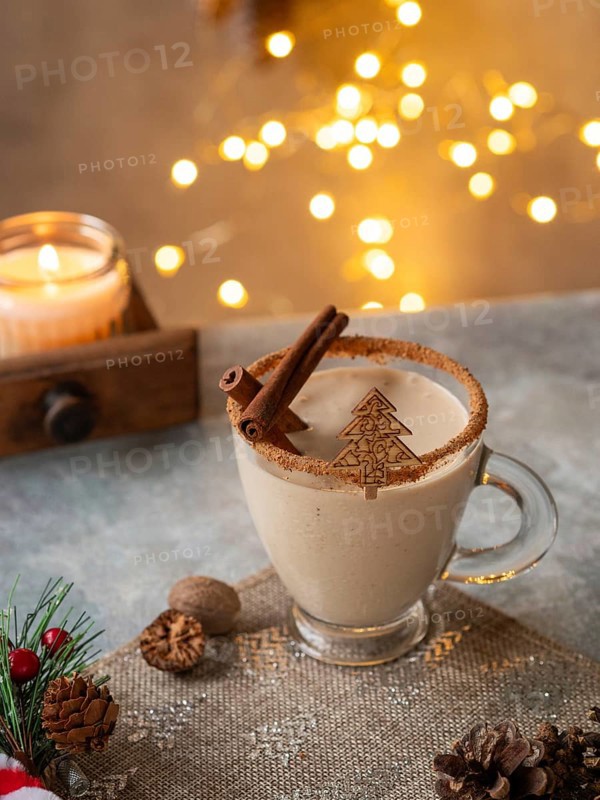Creamy christmas eggnog featuring cinnamon sticks, nutmeg, and a festive christmas tree decoration
