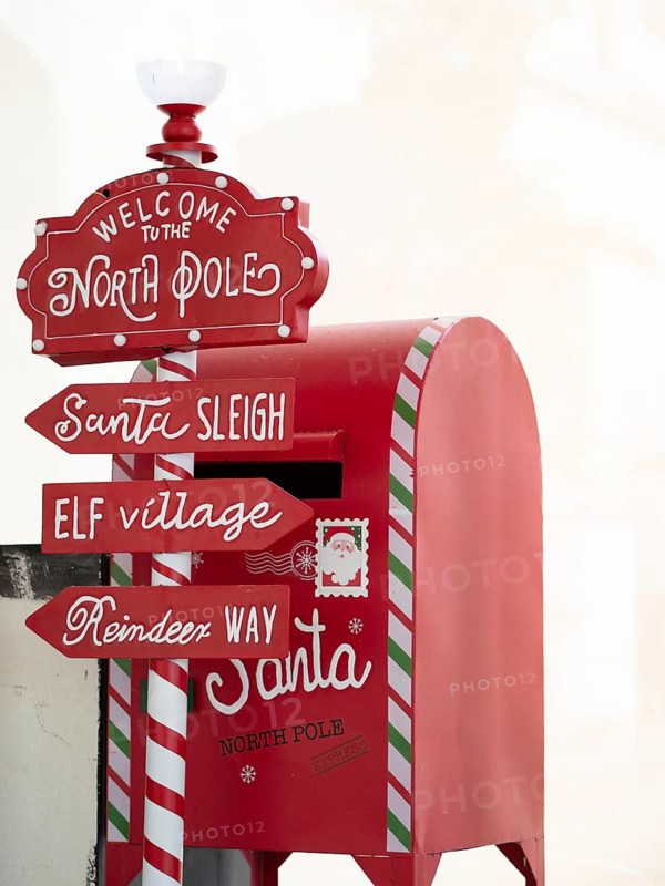 Red mailbox collecting letters to santa near directional signs to north pole