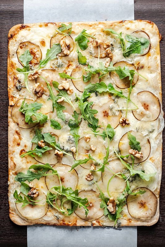 Gourmet flatbread preparing with pear, gorgonzola cheese, walnuts, and fresh arugula