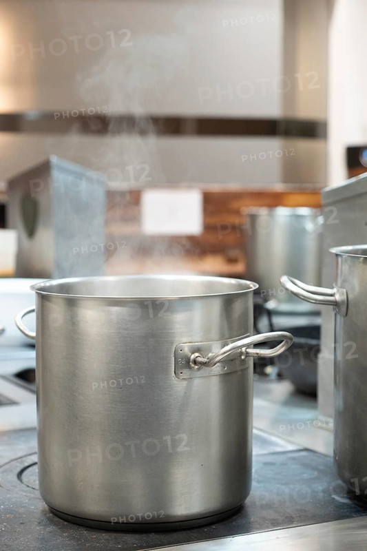 Commercial kitchen pot steaming on a restaurant stove, preparing food for cooking