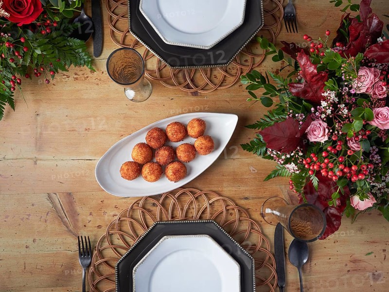 Crispy croquettes on an elegant white serving platter at a decorated dinner table