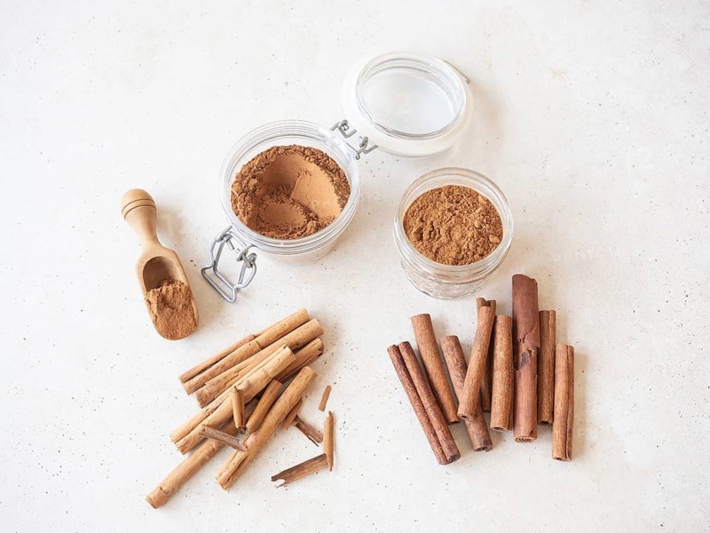 Cinnamon sticks, cassia and ceylon, with ground powder in jars and a wooden scoop