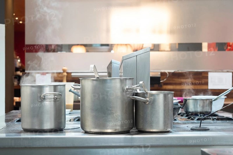 Steaming pots on a commercial stove in a professional kitchen, preparing food