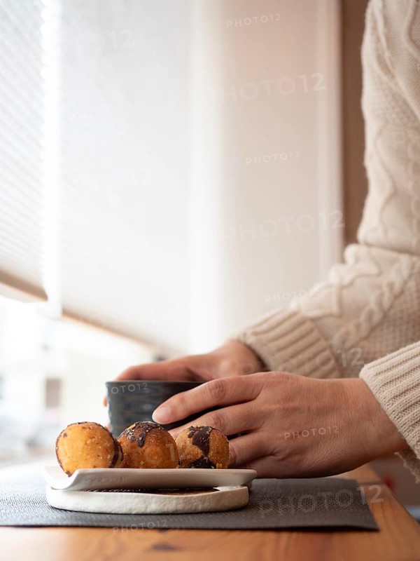 Woman enjoying a relaxing moment with coffee or tea and cookies in a cozy cafe by the window