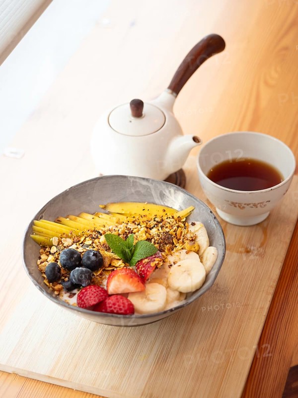 Oatmeal with granola, mango, banana, blueberries and strawberries served with tea