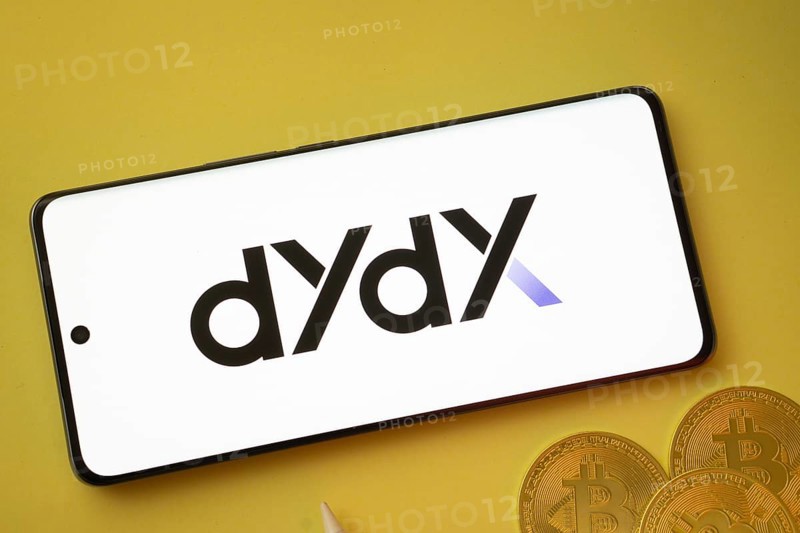 Dhaka, Bangladesh- 03 Oct 2025:Dydx logo on smartphone screen near Bitcoin coin and QR code on yellow background