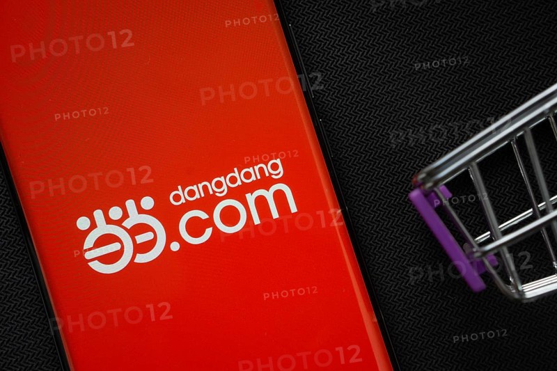 Dhaka, Bangladesh- 03 Oct 2025: A smartphone displaying the Dangdang.com logo next to a miniature shopping cart on a background