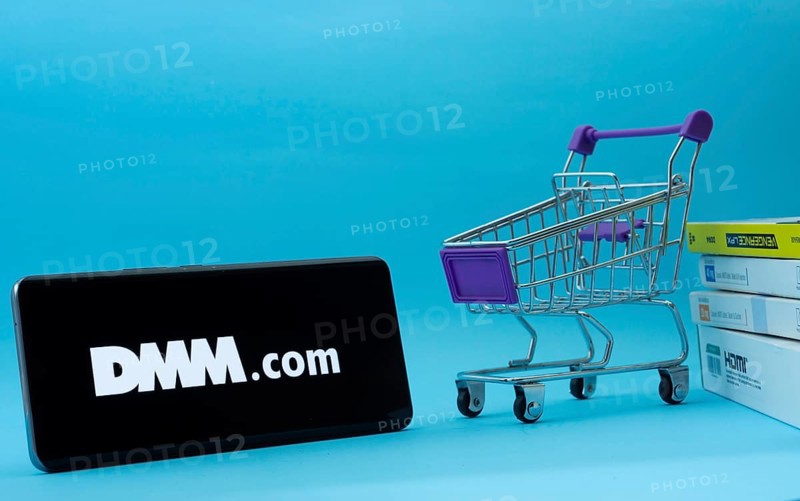 Dhaka, Bangladesh- 03 Oct 2025: Smartphone with Dmm.com logo next to a small shopping cart and boxes against a blue background