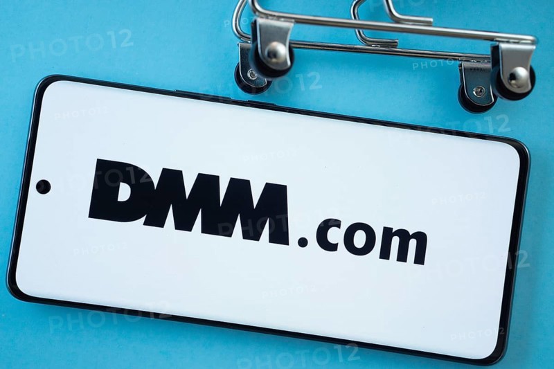 Dhaka, Bangladesh- 03 Oct 2025: Smartphone screen showing the Dmm.com logo with shopping cart wheels on a blue background