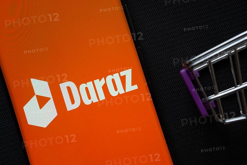 Dhaka, Bangladesh- 03 Oct 2025: A smartphone displaying the Daraz logo next to a miniature shopping cart on a background