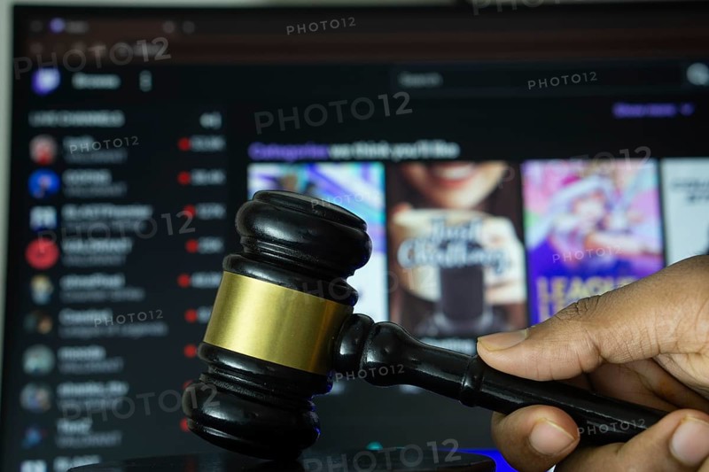 Dhaka, Bangladesh- 30 Sep 2025: A hand holds a gavel in front of a computer screen displaying Twitch website