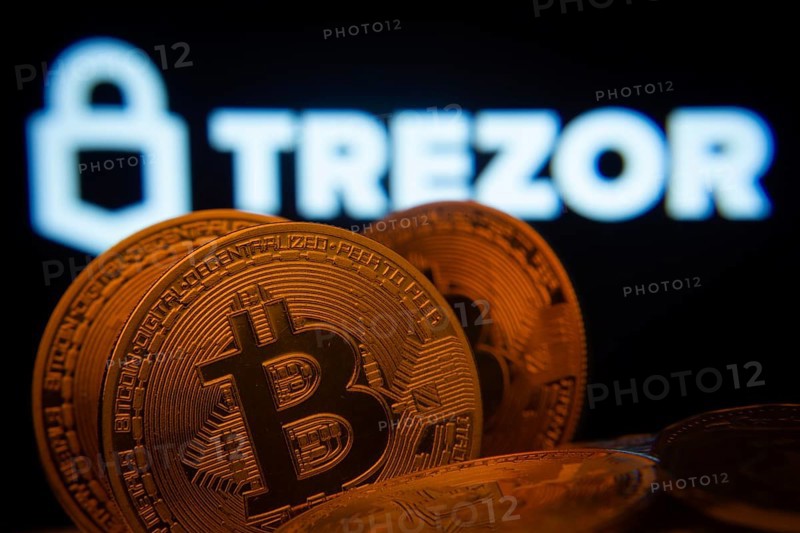 Dhaka, Bangladesh- 20 Sep 2025: Close-up of Bitcoin coins with the Trezor logo visible on a screen in the background