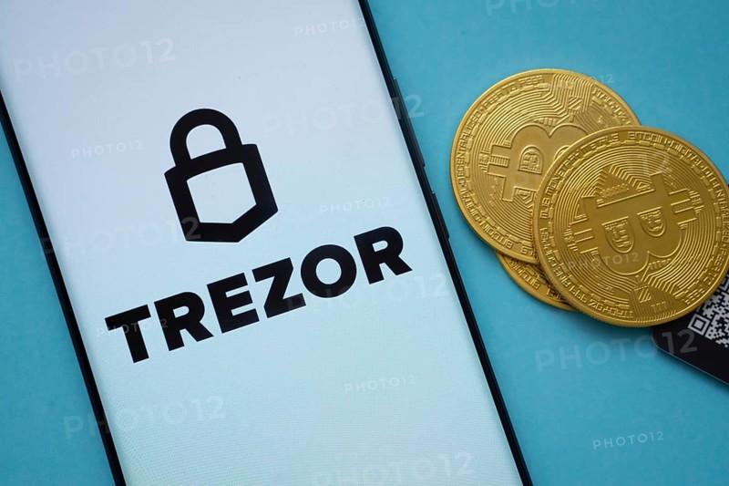 Dhaka, Bangladesh- 30 Sep 2025: Trezor logo on smartphone screen near Bitcoin coin and QR code on blue background