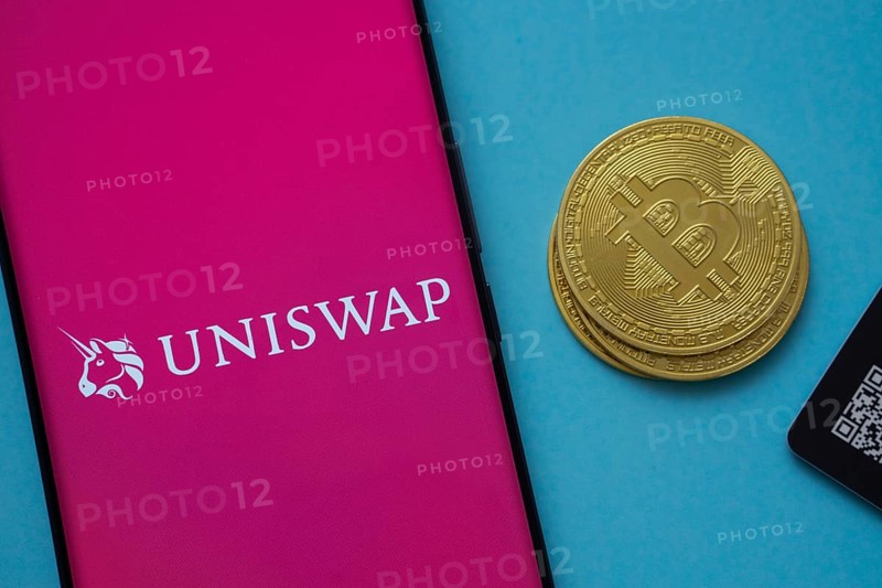 Dhaka, Bangladesh- 19 Sep 2025: Uniswap logo on smartphone screen near Bitcoin coin and QR code on blue background