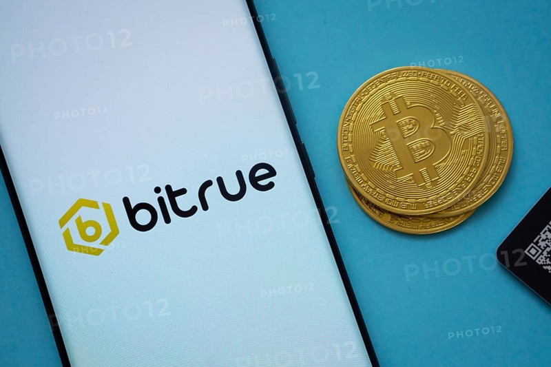 Dhaka, Bangladesh- 03 Sep 2025: Bitrue logo on smartphone screen near Bitcoin coin and QR code on blue background