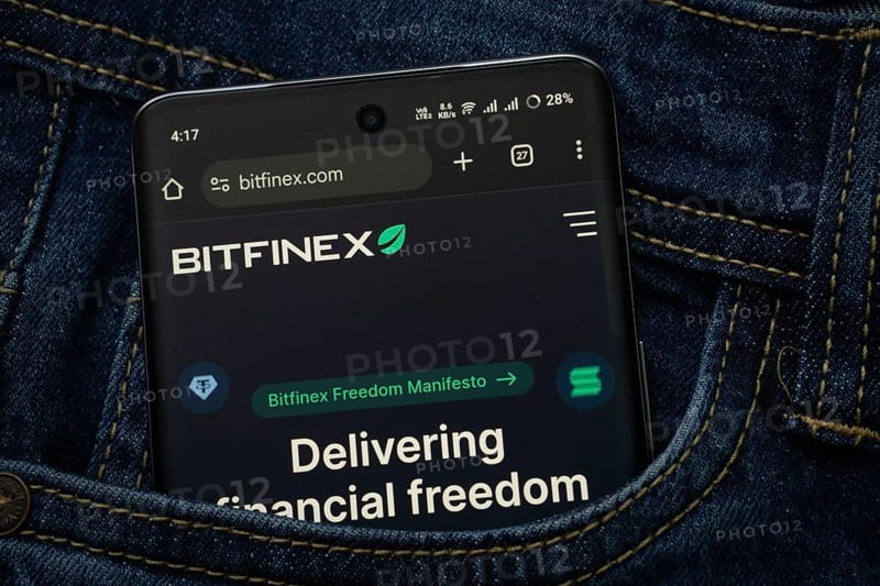 Dhaka, Bangladesh- 15 June 2025: A smartphone displaying the Bitfinex.com web interface peeks out of a denim pocket
