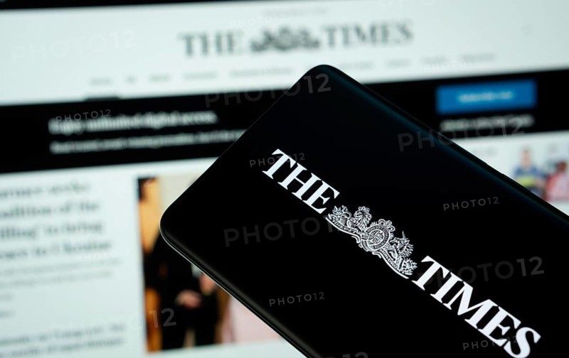 Dhaka, Bangladesh - 18 March 2025: The logo of the times is displayed on a smartphone screen, and the website is visible on a computer screen in the background
