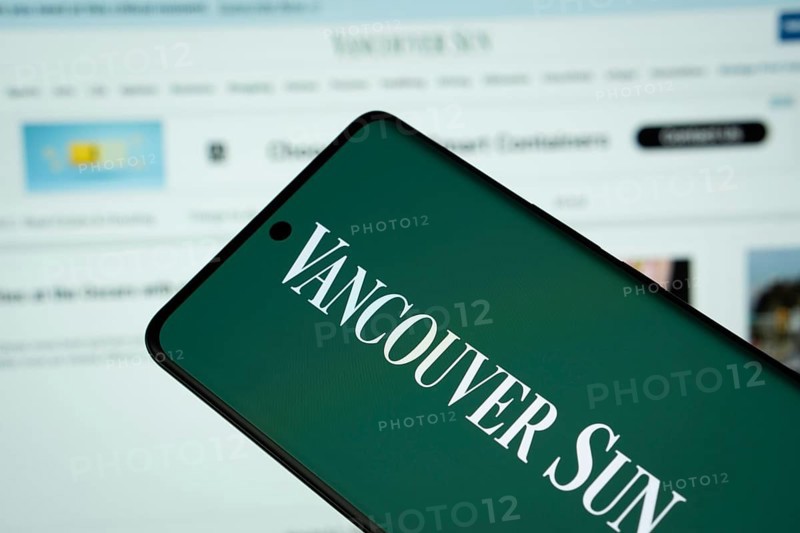 Dhaka, Bangladesh - 18 March 2025: The logo of Vancouver Sun is displayed on a smartphone screen, and the website is visible on a computer screen in the background