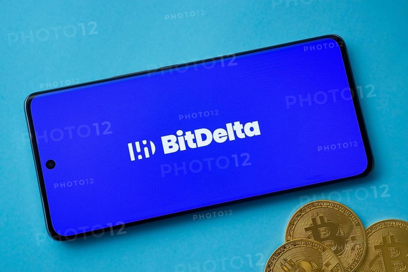 Dhaka, Bangladesh- 02 June 2025: BitDelta logo on smartphone screen near Bitcoin coin and QR code on blue background