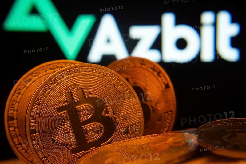 Dhaka, Bangladesh- 02 June 2025: Close-up of Bitcoin coins with the Azbit logo visible on a screen in the background