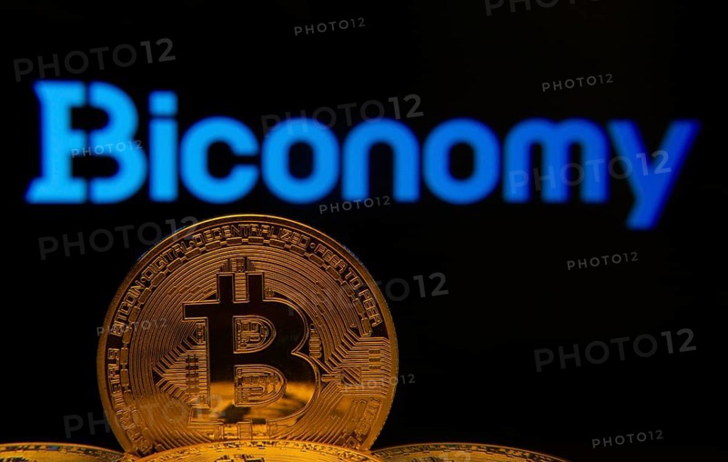 Dhaka, Bangladesh- 02 June 2025: Close-up of Bitcoin coins with the Biconomy logo visible on a screen in the background