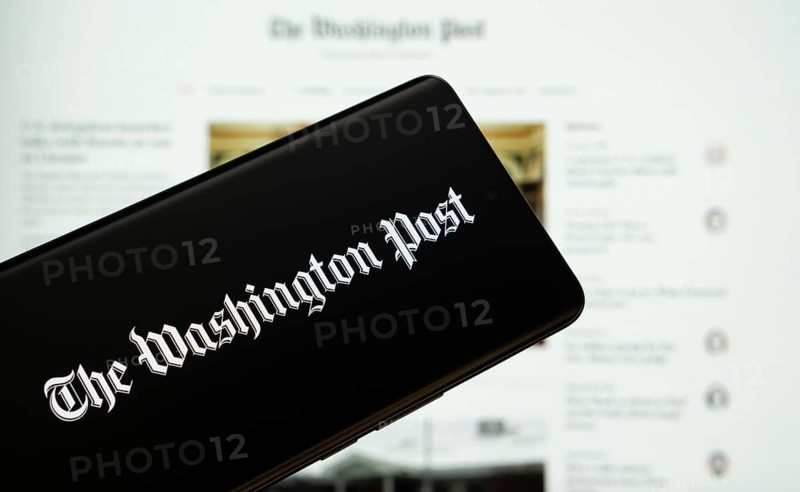 Dhaka, Bangladesh - 18 March 2025: The logo of the wall street journal is displayed on a smartphone screen, and the website is visible on a computer screen in the background