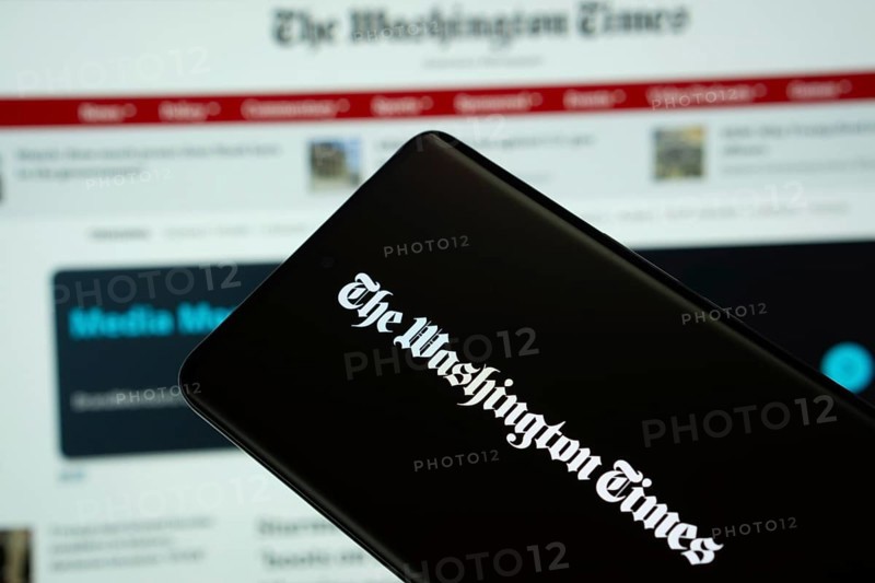 Dhaka, Bangladesh - 18 March 2025: The logo of the washinton times is displayed on a smartphone screen, and the website is visible on a computer screen in the background