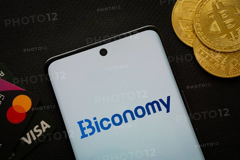 Dhaka, Bangladesh- 02 June 2025: Smartphone displaying Biconomy logo surrounded by Bitcoin coins and payment cards