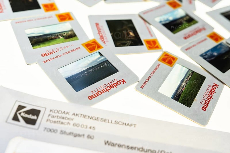 Many framed Kodachrome slides on a light table with magnifying glass, top shot