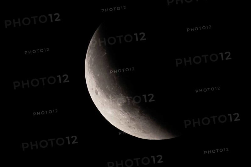 After a total lunar eclipse, the moon appears shortly after its rise in the evening sky as a so-called blood moon in front of it then begins to emerge from the Earth's umbra, Frankfurt am Main, Hesse, Germany