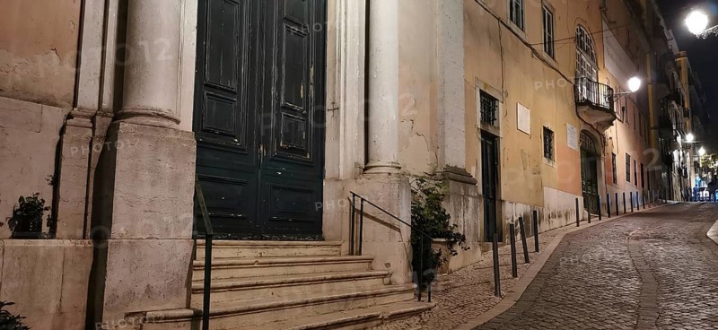 Cobblestone street in an old town at night, lined with historic buildings, Lisbon, Portugal