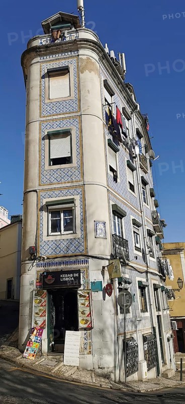 A tall, narrow building on a sloping street with typical facades, Lisbon, Portugal