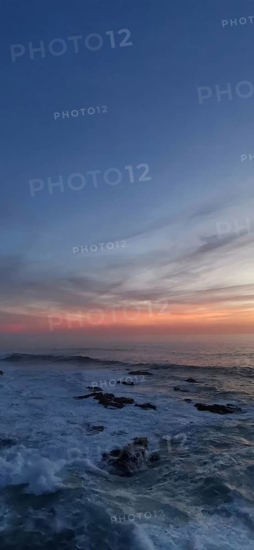 Sunset over a peaceful ocean with rocks in the foreground, hiking the Fisherman's trail, Rota Vicentina, Porto Covo, Alentejo region, Portugal