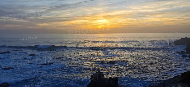 Sunset over a peaceful ocean with rocks in the foreground, hiking the Fisherman's trail, Rota Vicentina, Porto Covo, Alentejo region, Portugal
