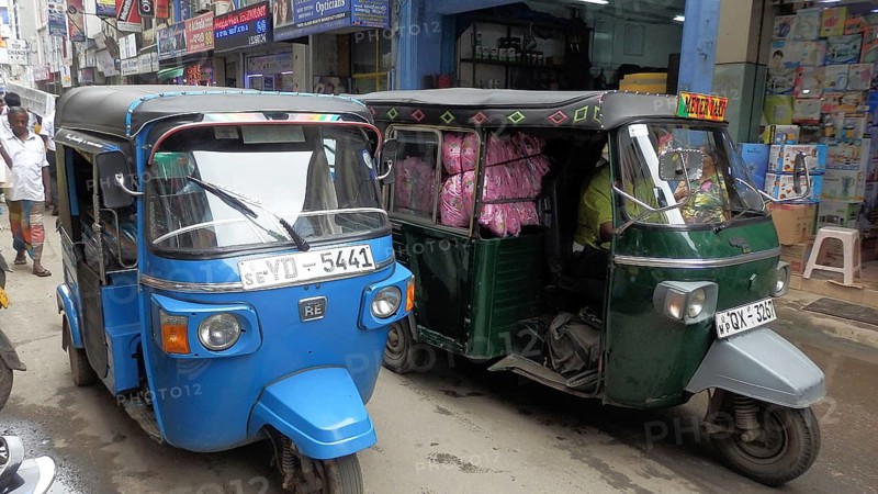 Colourful tuktuks park along a lively city street with shops, Sri Lanka