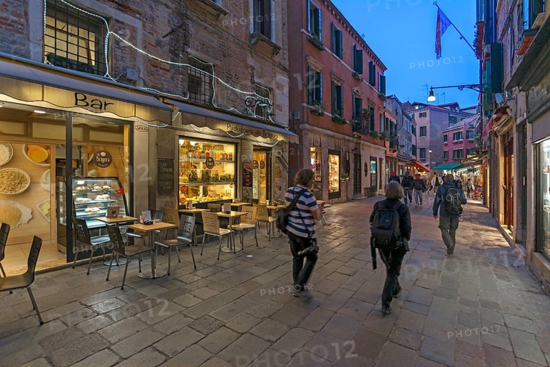 Photographers traveling in the old town of Venice, Veneto, Italy in the evening