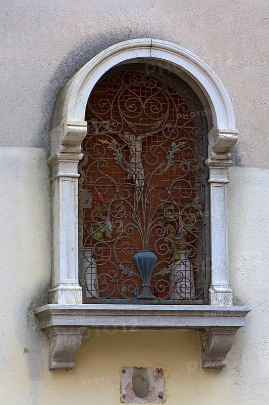 Devotional niche with a Jesus cross behind an ornate grid, Venice, Veneto, Italy