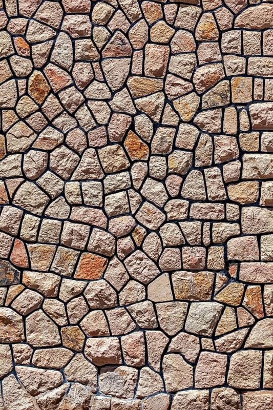 Irregular natural stone wall with brown-beige stones in rustic pattern, a natural stone wall as a background