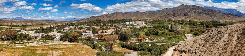 Panorama of a green village nestled in hilly and mountainous landscape, roads through the Quebrada de Cafayate countryside near Salta in Argentina