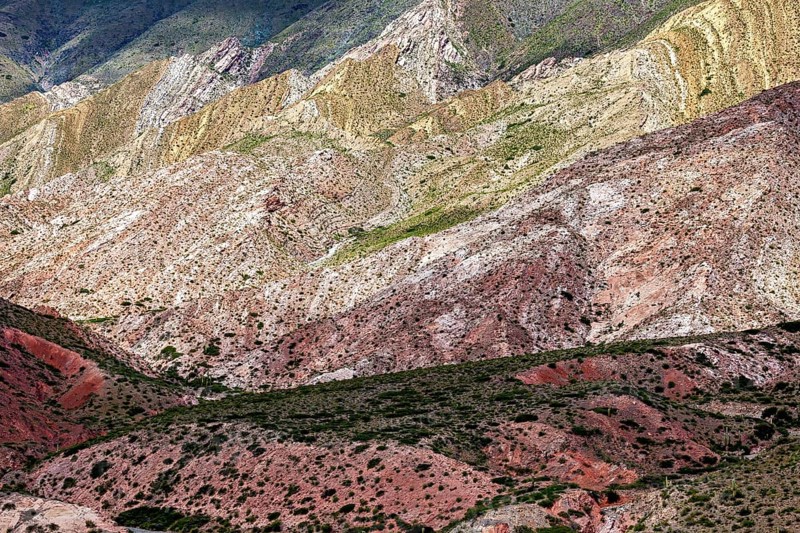 Mountains with diverse colors and natural patterns rise from the vegetation, the landscape and colorful rock formations of the Quebrada de Cafayate near Salta in Argentina